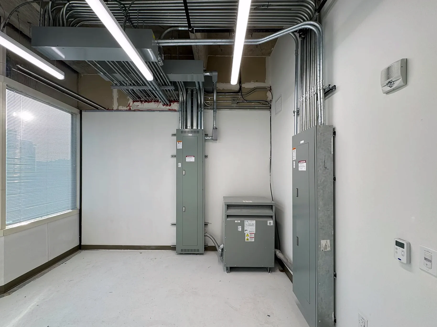 Electrical room with Eaton panelboards, transformer and EMT conduit installed by Texas A&E